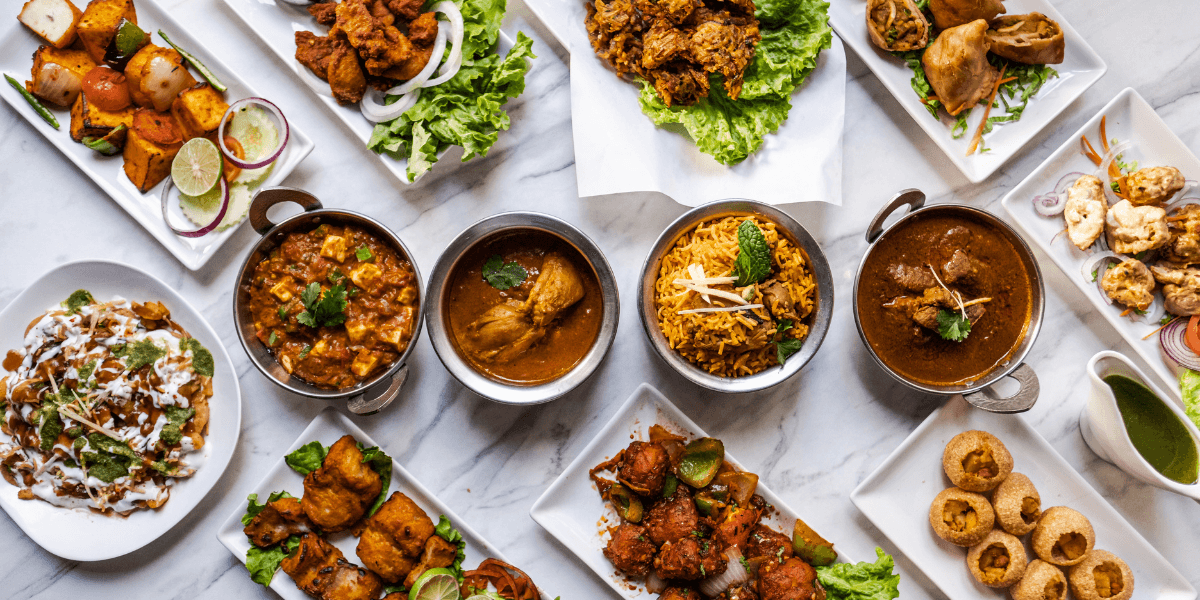 An array of vibrant Indian dishes, including curries, kebabs, rice, and appetizers.