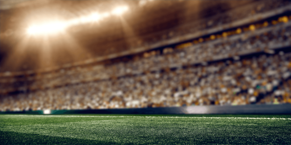 Blurred view of a stadium field with bright lights and a large crowd