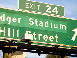 Green freeway sign directing traffic toward Dodger Stadium and Hill Street at Exit 24.