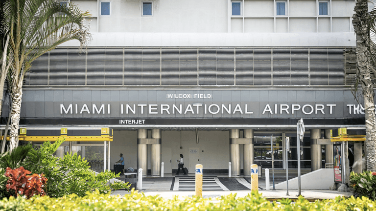 Facade of Miami International Airport showing entrance and signage with tropical landscaping