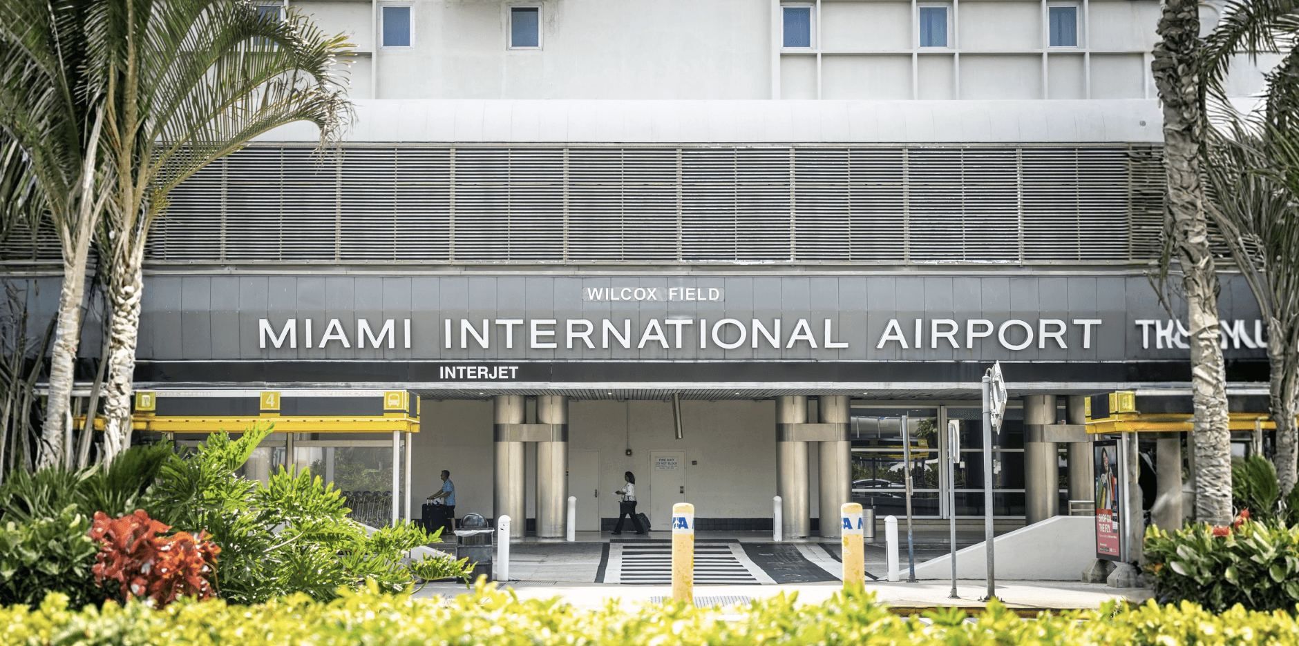 Facade of Miami International Airport showing entrance and signage with tropical landscaping