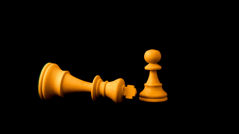 A fallen king chess piece next to a standing pawn on a black background