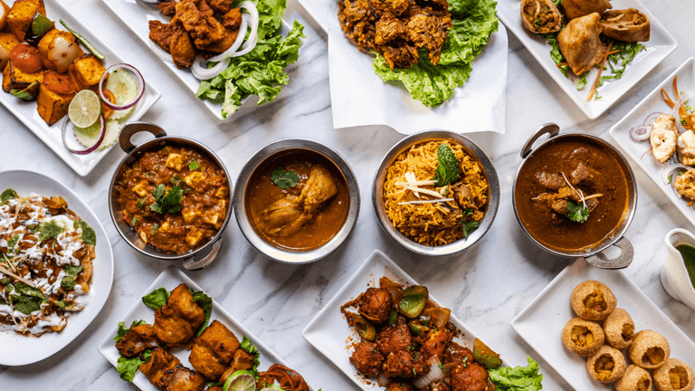 An array of vibrant Indian dishes, including curries, kebabs, rice, and appetizers.