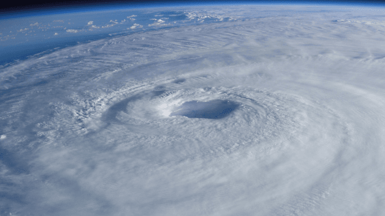 Aerial view of a swirling hurricane with a prominent eye and dense cloud cover