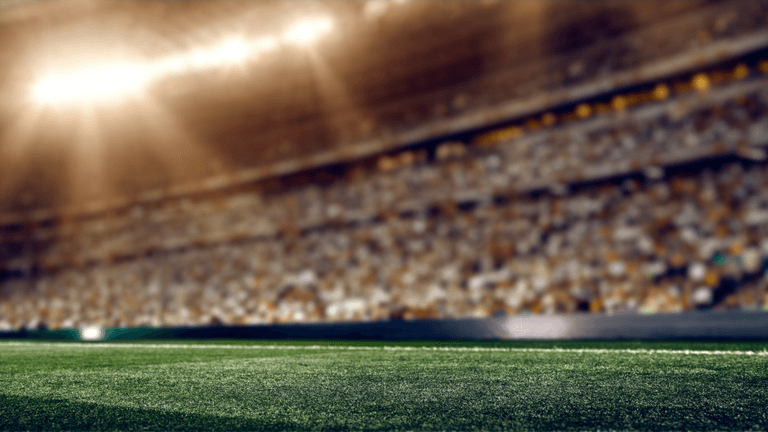 Blurred view of a stadium field with bright lights and a large crowd