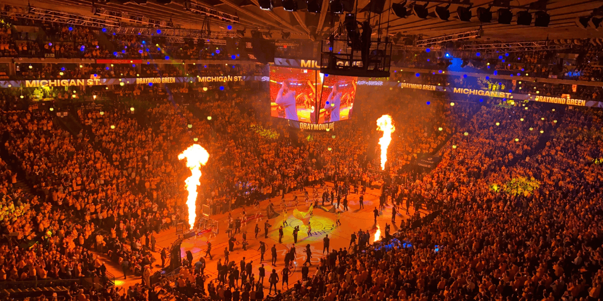Fans fill an arena during NBA Summer League player introductions with flames and large video screens.