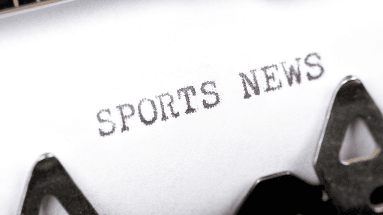 Typewriter printing the words "Sports News" on a sheet of paper.