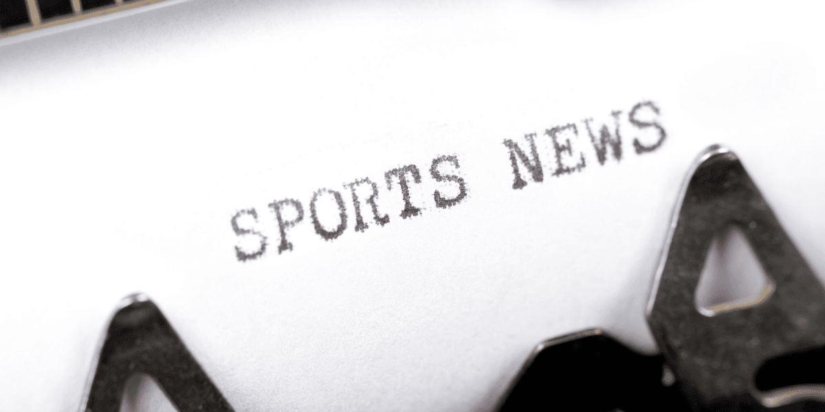 Typewriter printing the words "Sports News" on a sheet of paper.