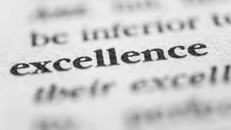 Close-up of the word "excellence" printed on a page in sharp focus.