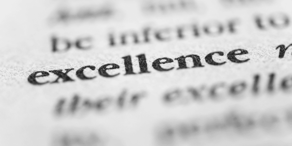 Close-up of the word "excellence" printed on a page in sharp focus.