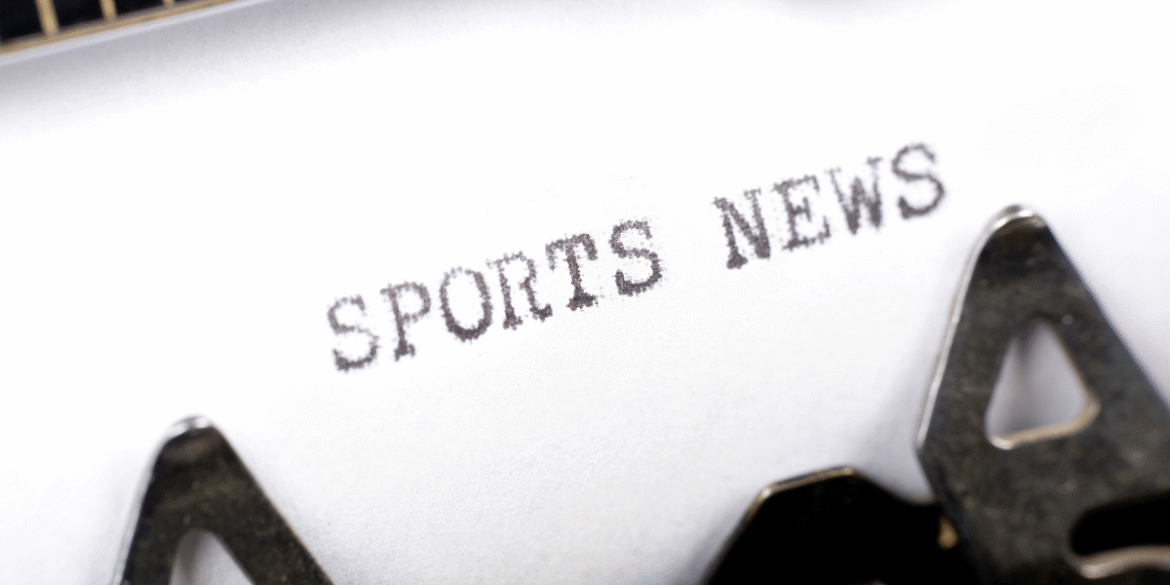 Typewriter printing the words "Sports News" on a sheet of paper.