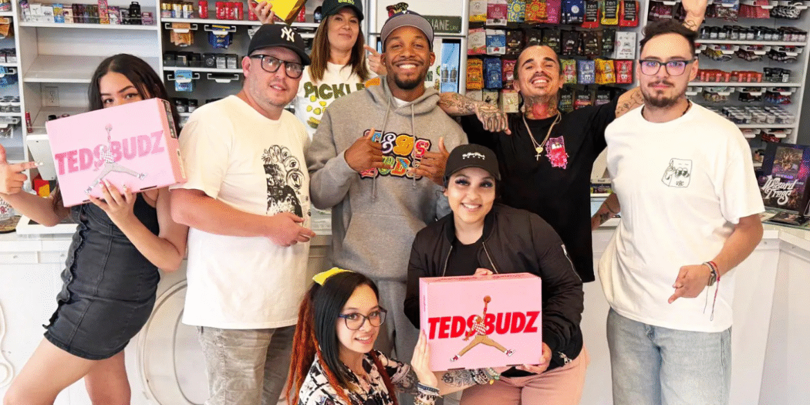 Group of smiling staff and visitors at Vallejo Relief Center holding pink Ted's Budz branded boxes inside the shop, with retail shelves in the background